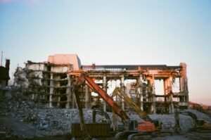 Construction machinery at a building demolition site during sunset.
